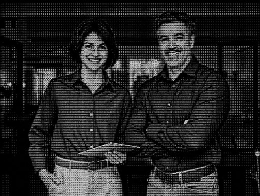 Black-and-white pixel-art portrait of two people standing indoors.